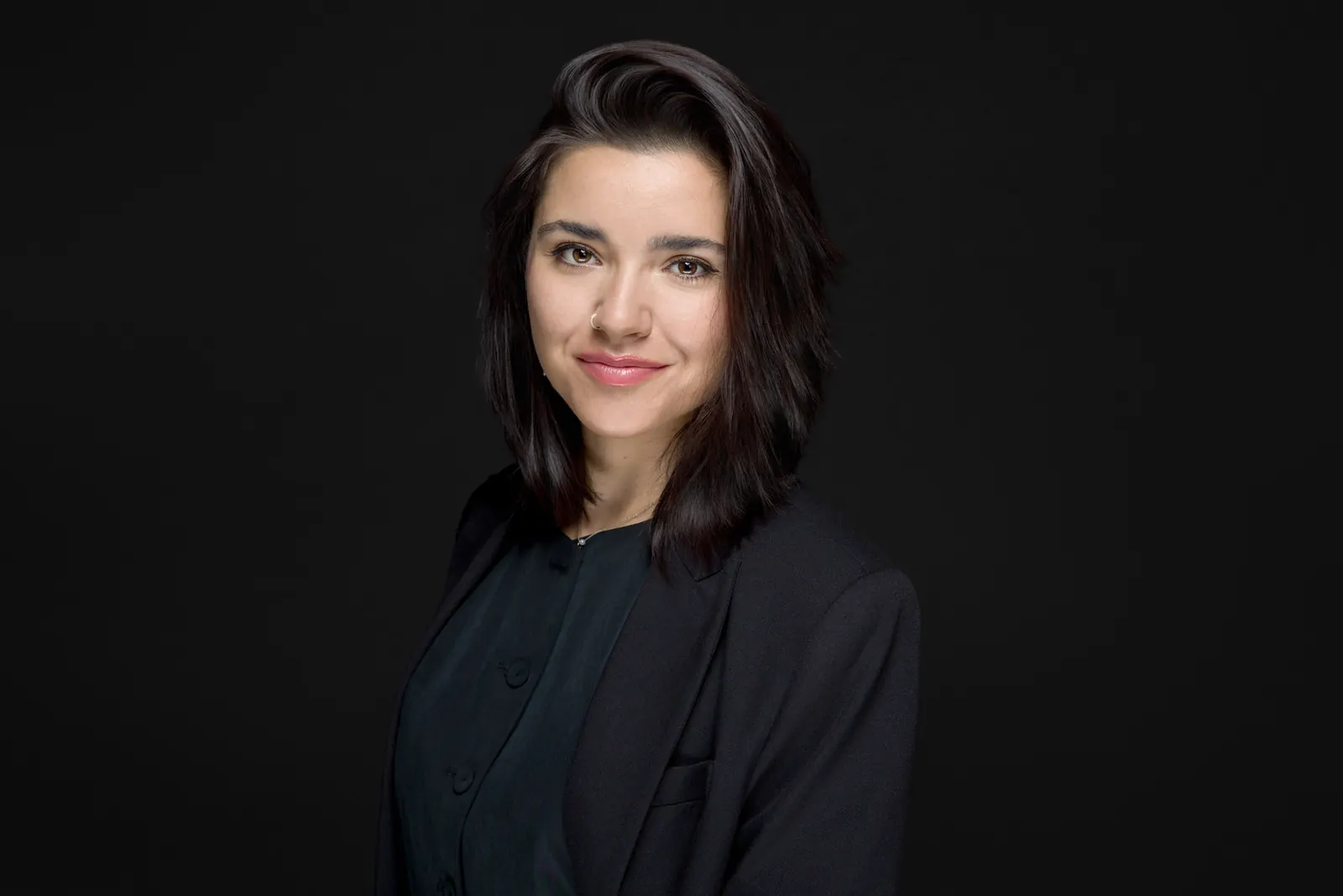 Business-Portrait vor schwarzem Hintergrund, schlichte dunkle Kleidung ohne Muster