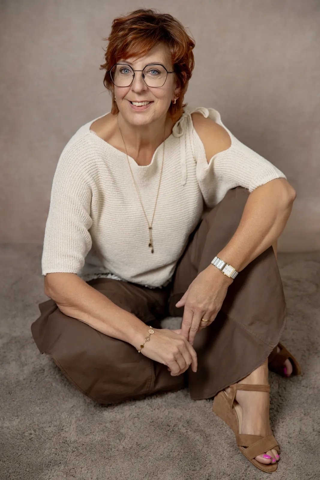 Frau im hellen Strickpullover sitzt entspannt auf dem Studioboden, Portrait in Chur