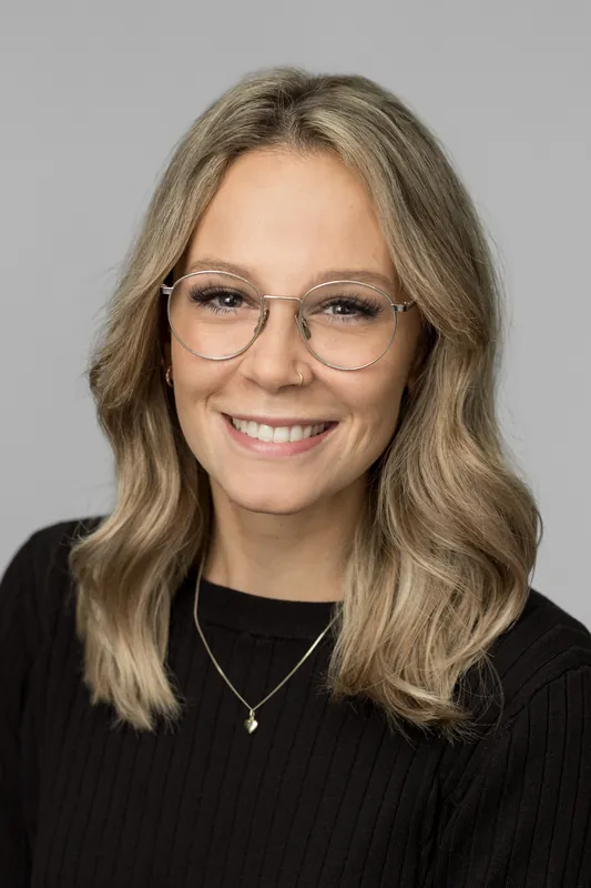 Bewerbungsfoto einer jungen Frau mit Brille und freundlichem Lächeln, heller Hintergrund – Standard-Bewerbungsbild im Fotostudio Chur