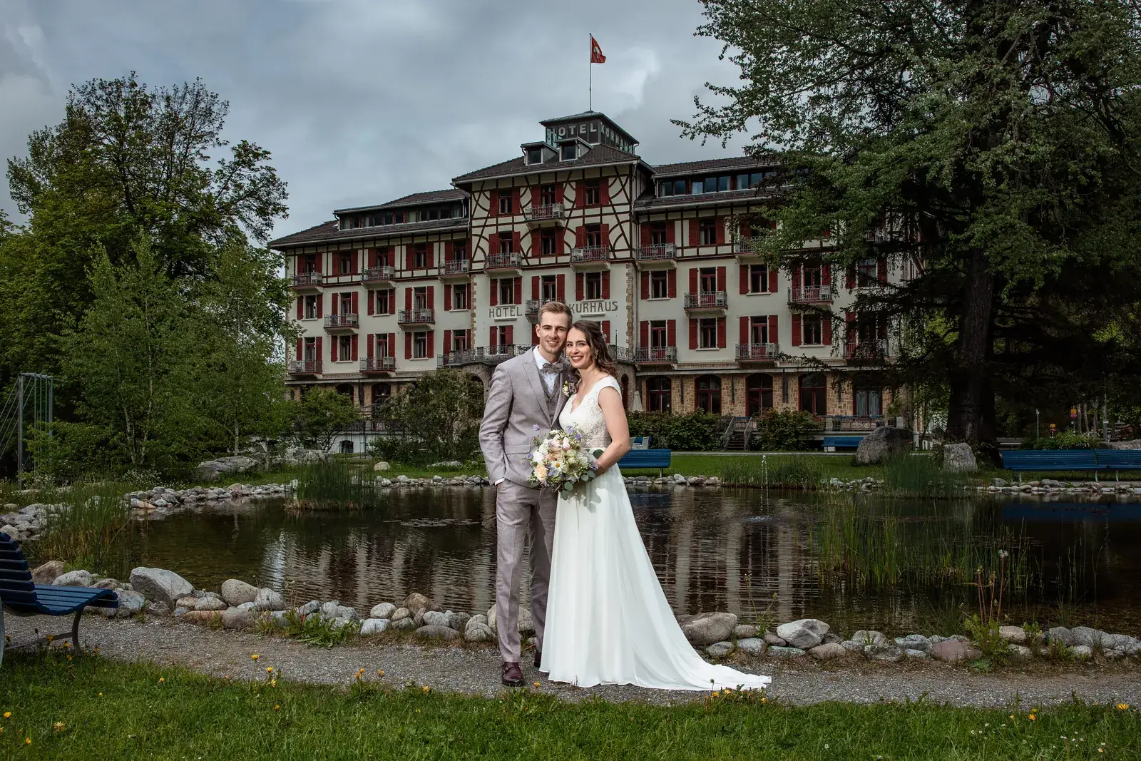 Brautpaar am Teich im Kurpark vor der Fassade des Hotel Kurhaus Bergün